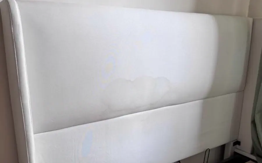 Before cleaning: white upholstered headboard